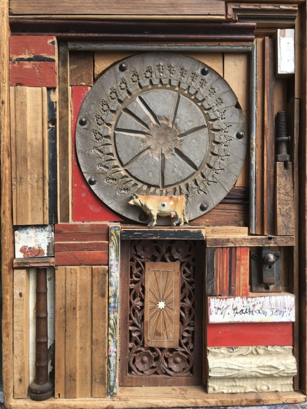 A salvaged-wood assemblage by Morris Nathanson built around an iron wheel, a carved panel and a toy cow